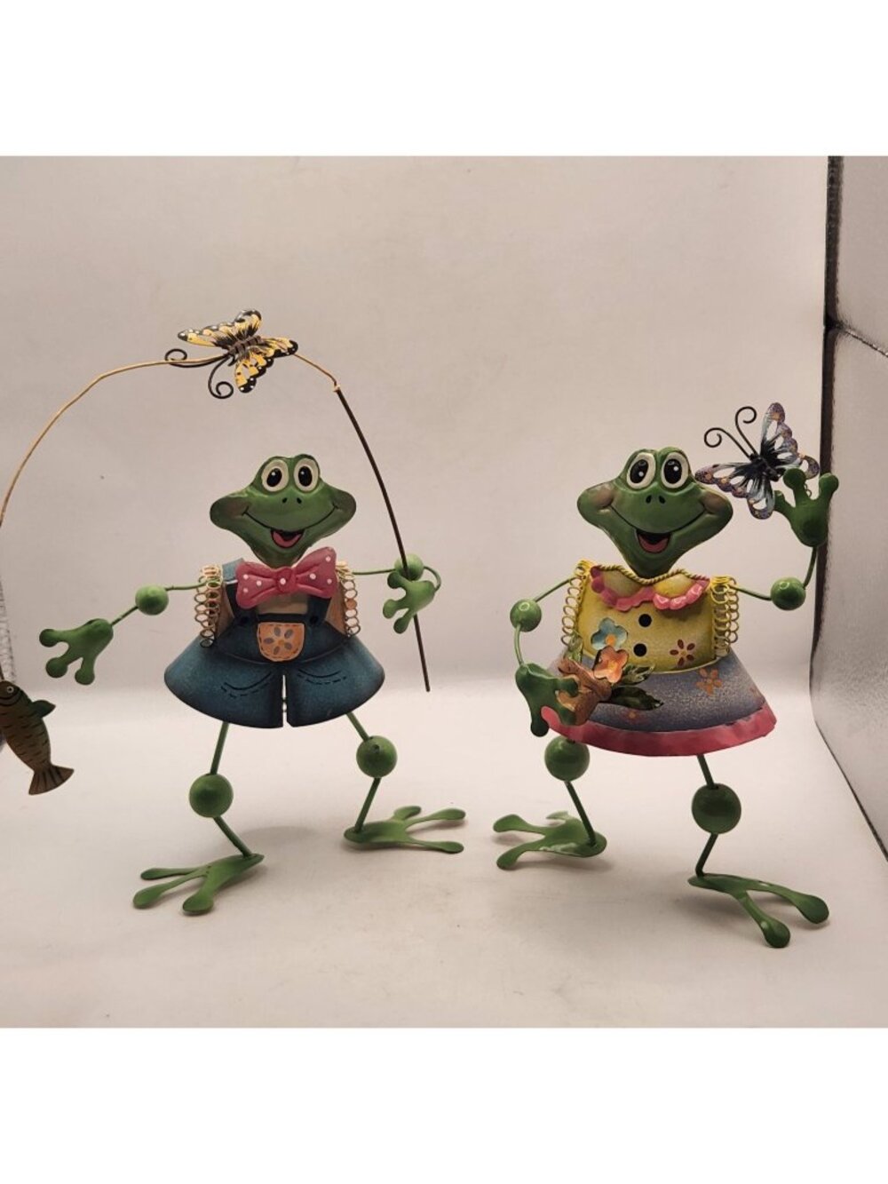 a pair of whimsical, hand-painted metal frog figurines designed as freestanding